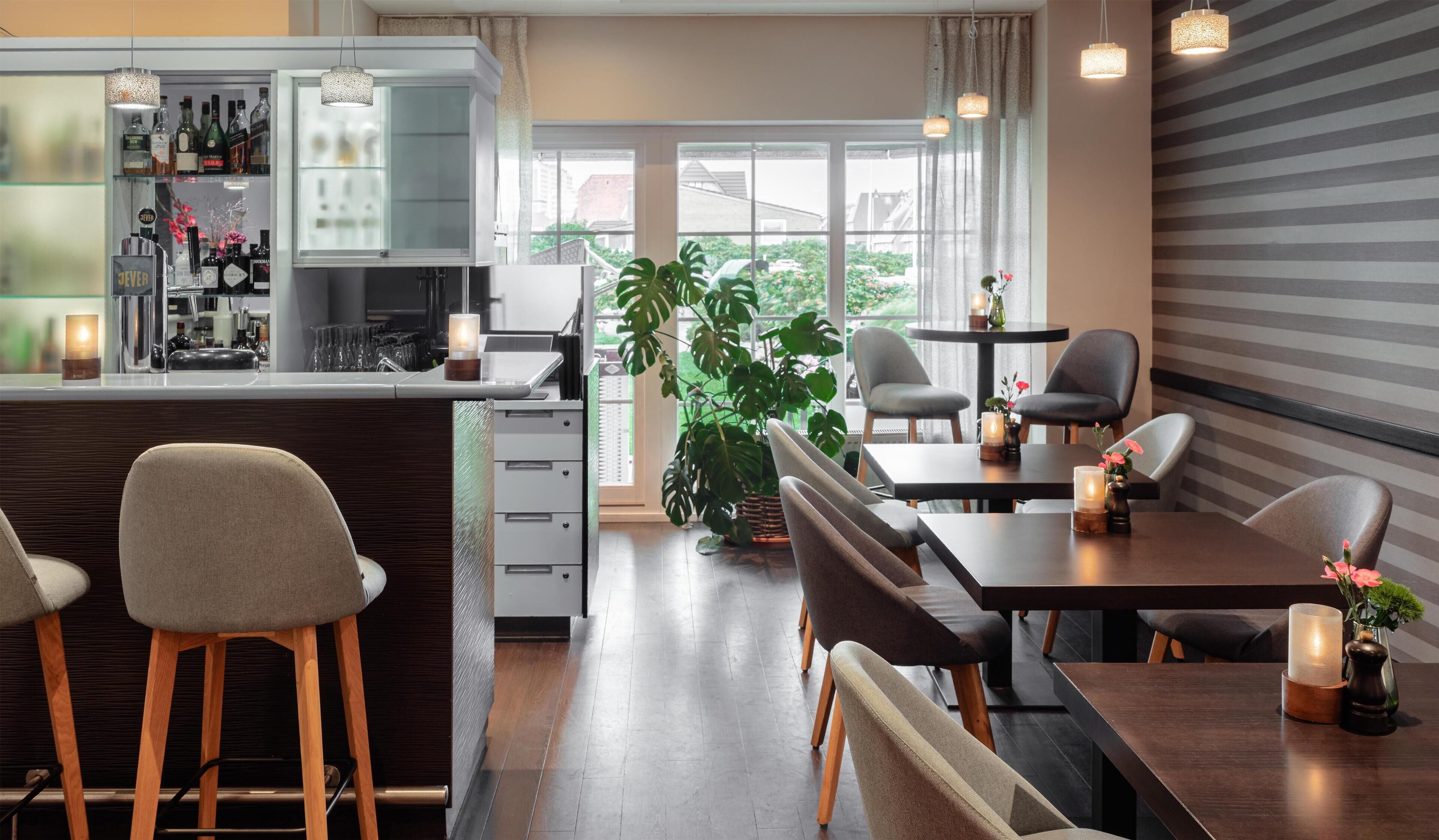A modern dining area with bar seating, a large window with a view, and a potted plant.