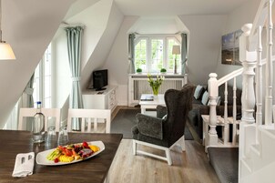 Una moderna stanza in stile loft con un tavolo da pranzo apparecchiato per un pasto, un'area salotto accogliente e vista sull'esterno attraverso una grande finestra.