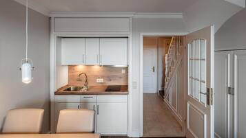 A compact kitchen with white cabinetry, a wooden countertop, and a built-in sink. There is a dining area with a table and chairs, and a staircase leading to another level.