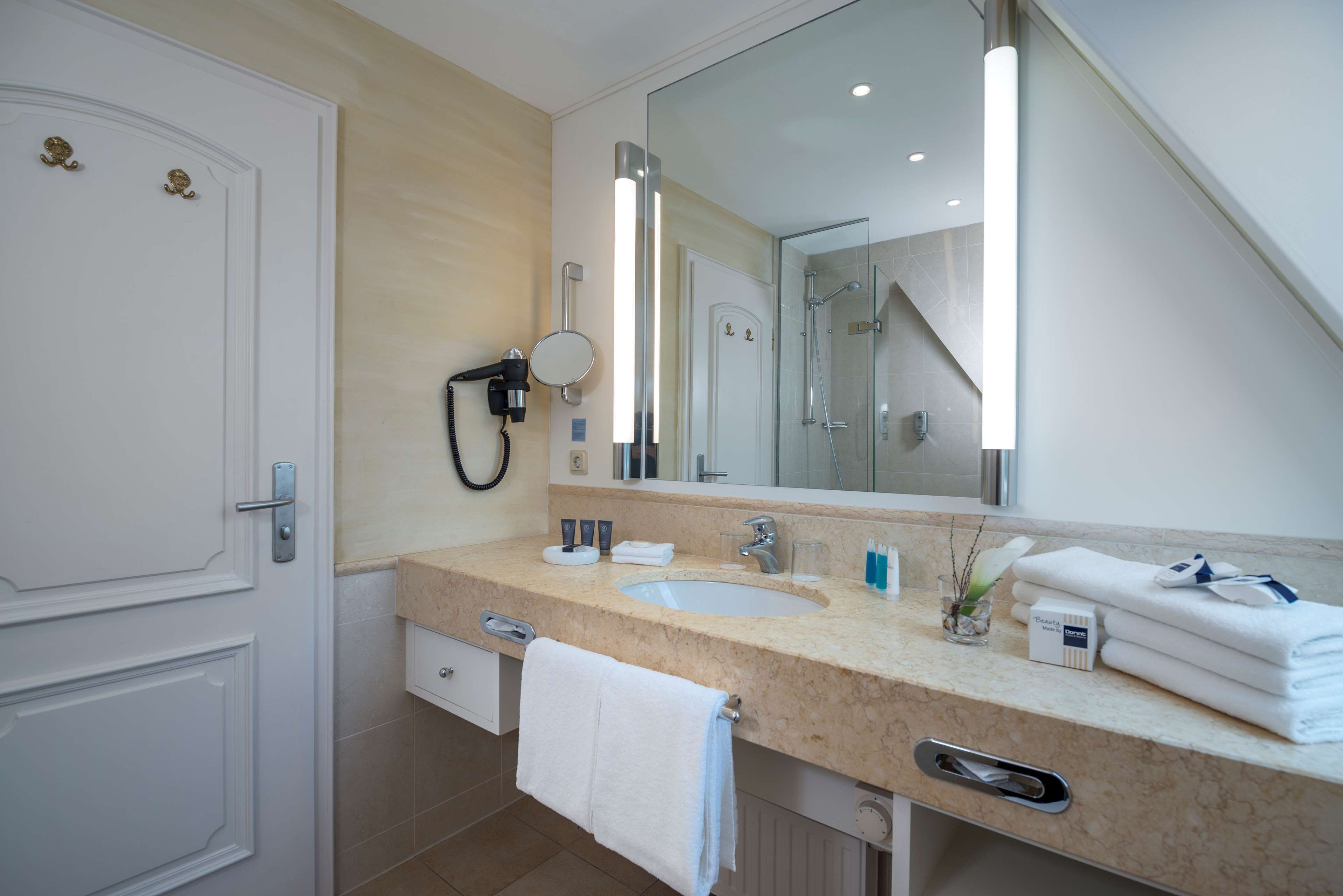 A modern bathroom with a large mirror, a sink, and a towel rack.
