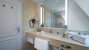 A modern bathroom with a large mirror, a sink, and a towel rack.