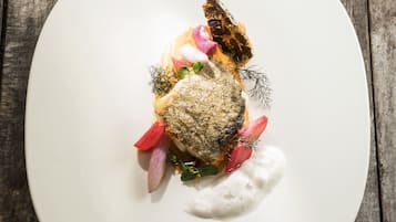 Une assiette blanche contenant un plat de poisson, posée sur une table en bois.
