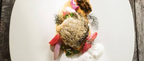 A white plate with a fish dish on a wooden table.