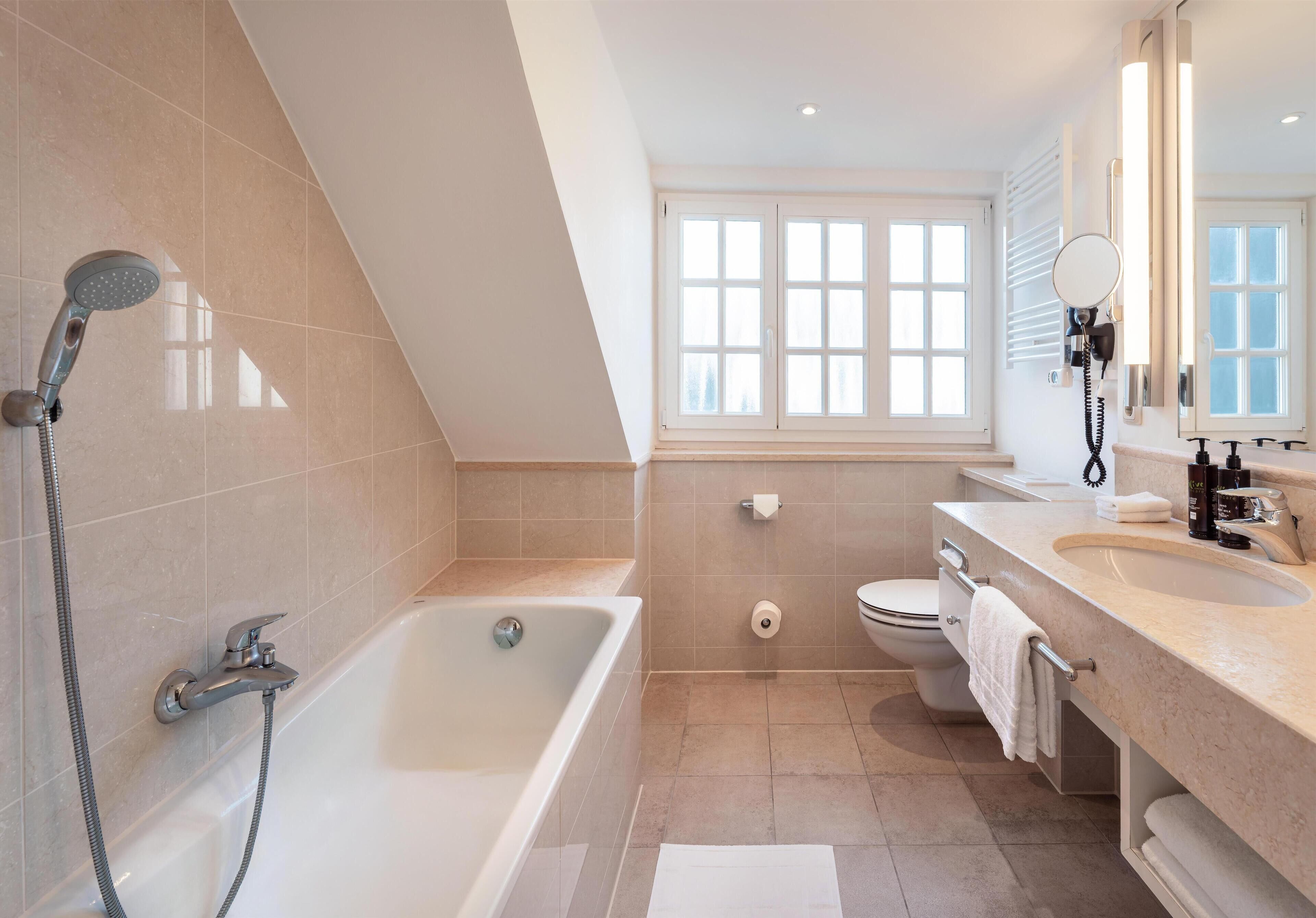 Un baño moderno con bañera, ducha, inodoro y tocador.