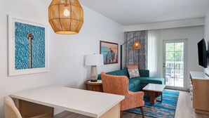 Una sala moderna con sofá, sillón, mesa de comedor y obras de arte en las paredes.