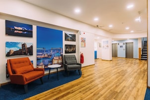 A spacious lobby with wooden flooring, a reception desk, and seating areas.