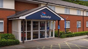 Un hôtel Travelodge avec une façade en briques, de grandes fenêtres et un auvent bleu.