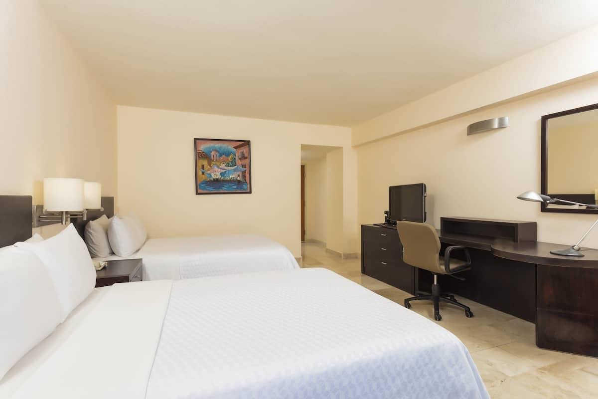 Habitació d'hotel amb dos llits, escriptori, cadira, televisió i un quadre a la paret.