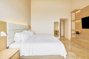 Una habitación de hotel moderna con una cama grande, un televisor de pantalla plana, estanterías de madera y un espejo.