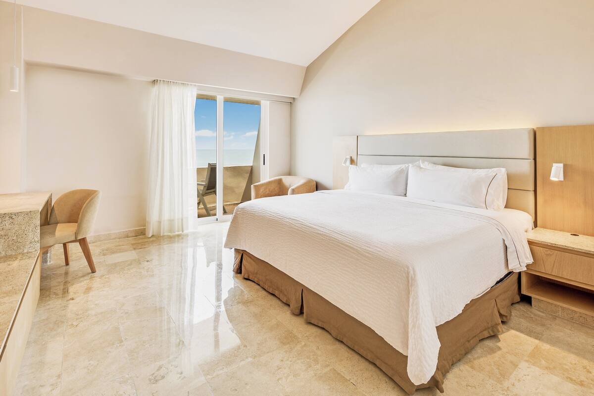 Una habitació d'hotel moderna amb un llit gran, una taula i una cadira.