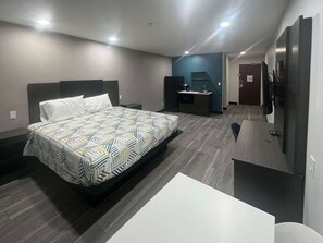 A modern hotel room with a large bed, a desk, a kitchenette, and a TV. - Studio 6 Oklahoma City - Moore/Norman (Oklahoma City)