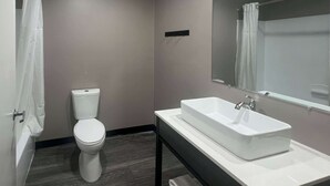 A modern bathroom with a toilet, a sink, and a mirror. - Studio 6 Oklahoma City - Moore/Norman (Oklahoma City)