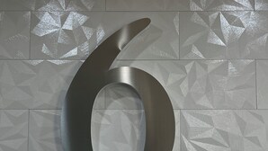 A large metallic number 6 on a textured wall. - Studio 6 Oklahoma City - Moore/Norman (Oklahoma City)