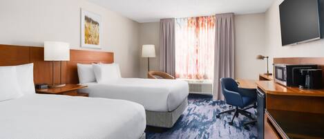 A hotel room with two beds, a desk with a TV, a chair, and a large window with curtains.
