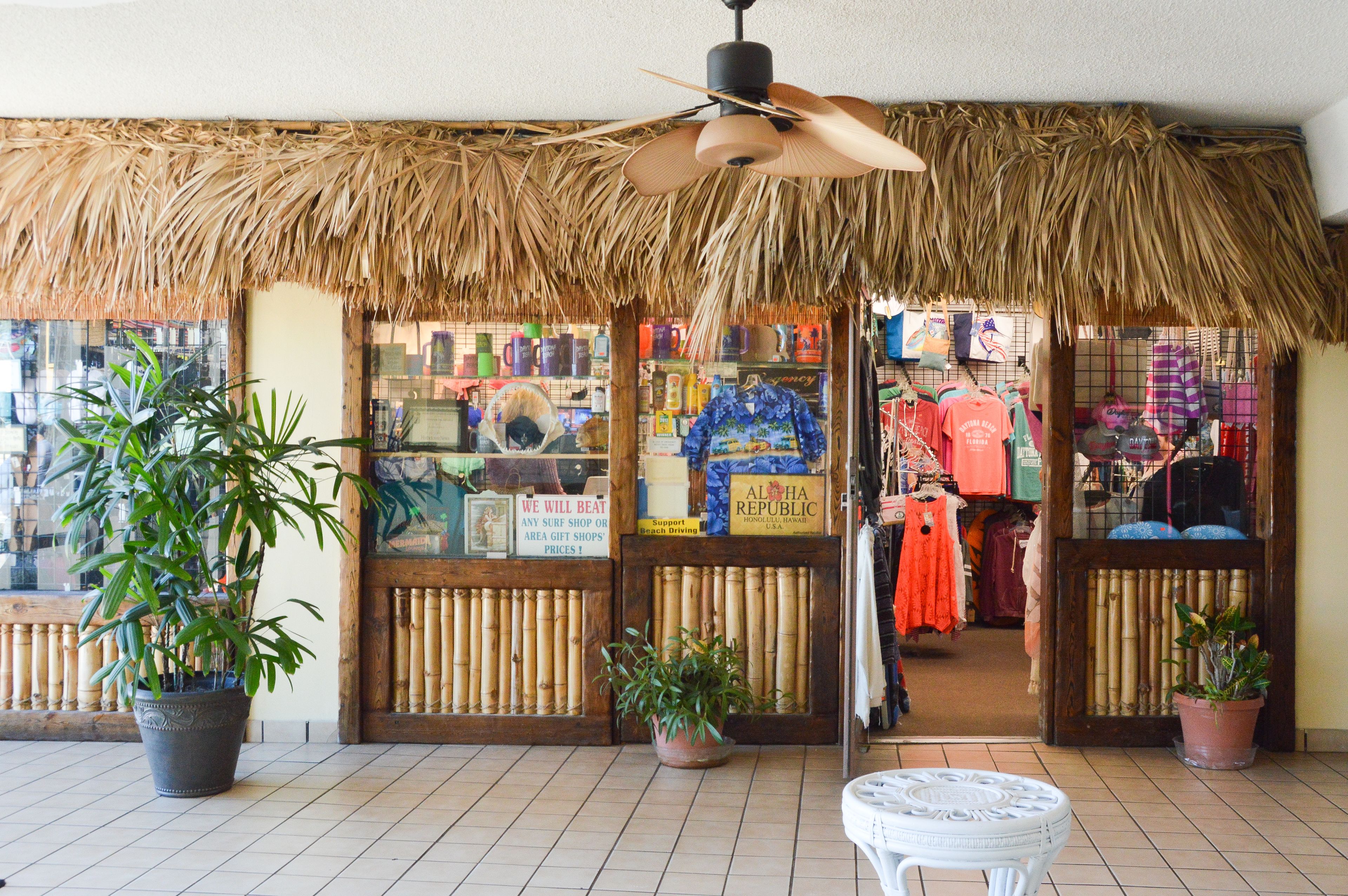 A shop with a thatched roof, bamboo fences, and potted plants.