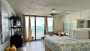 Une chambre d’hôtel équipée d’un lit, d’un bureau, d’une chaise, d’un canapé, d’un ventilateur de plafond et offrant une vue sur l’océan.