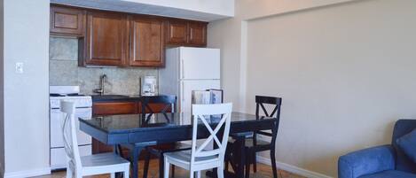 A modern kitchen with wooden cabinets, a white refrigerator, and a dining area with a table and chairs.