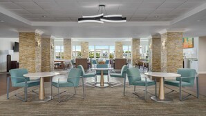 A lobby with multiple seating areas, stone pillars, and a view of the outdoors.