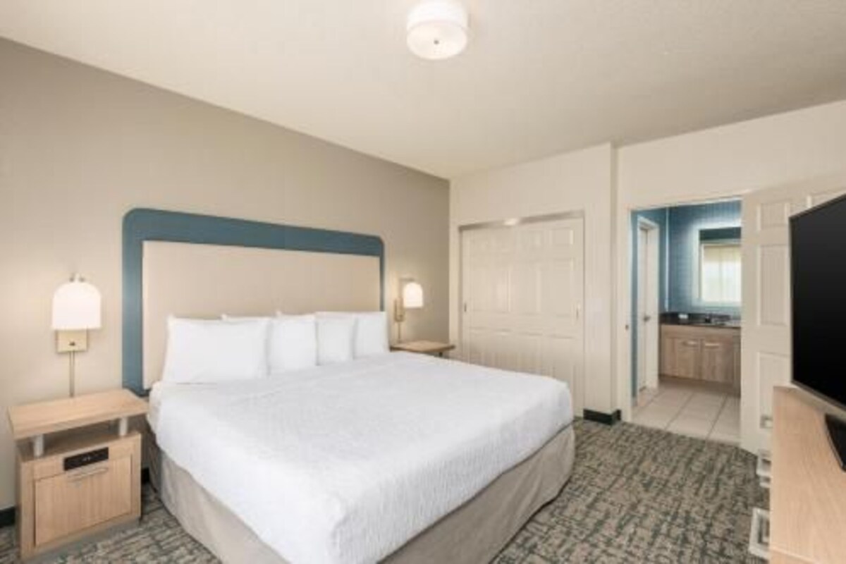 A hotel room with a large bed, bedside lamps, a desk, and a wardrobe.