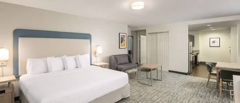 A hotel room with a large bed, a desk, a chair, and a sofa.