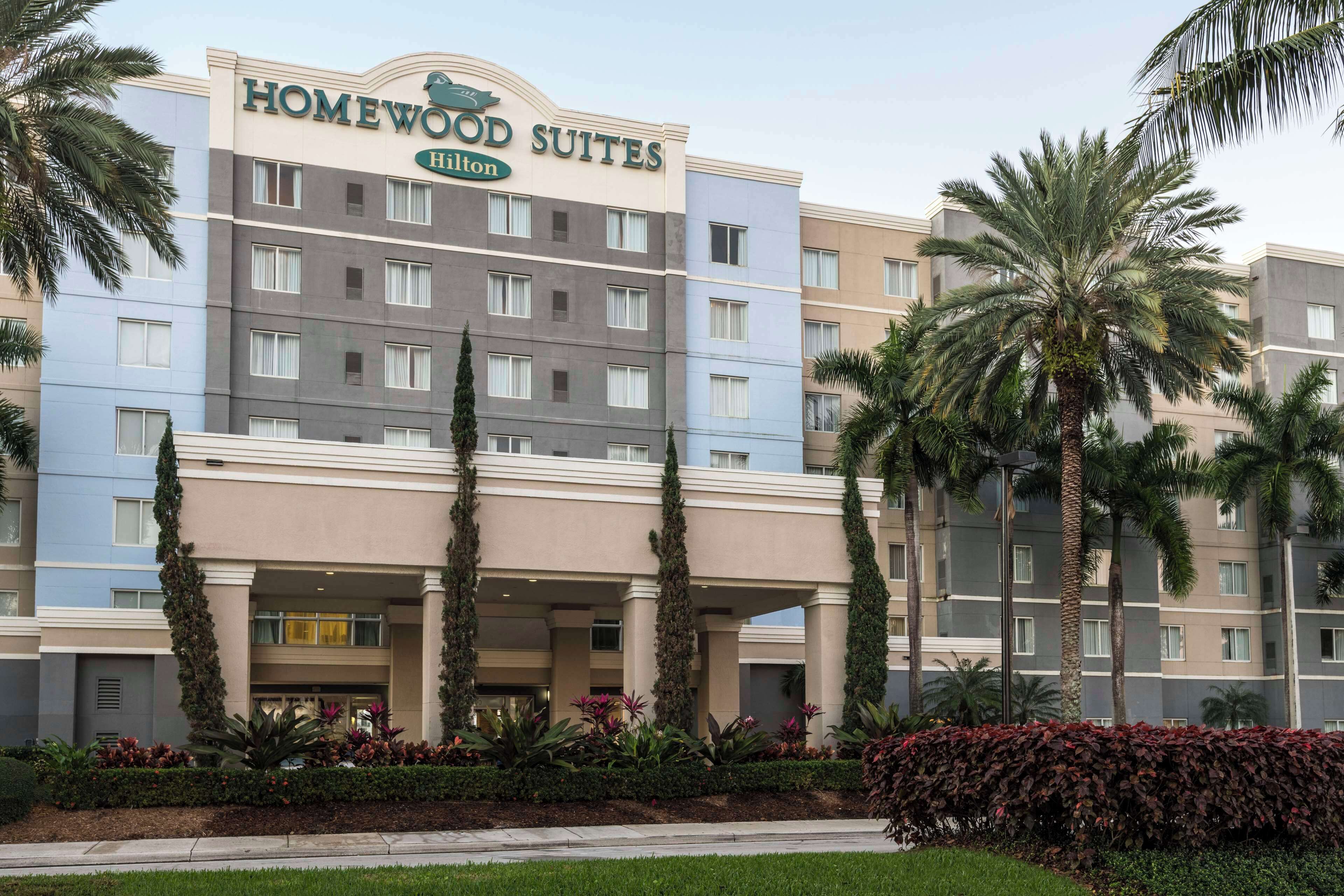 A multi-story hotel with a sign reading "HOMEWOOD SUITES Hilton."