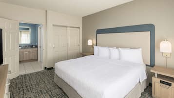 A hotel room with a large bed, a bedside table, a TV, and a bathroom visible through an open door.