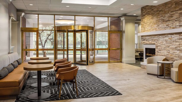 A modern lobby with a central seating area, a fireplace, and a view through a glass wall. - Homewood Suites by Hilton Washington, D.C. Downtown (Washington)