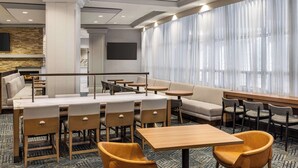 A modern hotel lobby with a seating area, a fireplace, and a large window with sheer curtains. - Homewood Suites by Hilton Washington, D.C. Downtown (Washington)