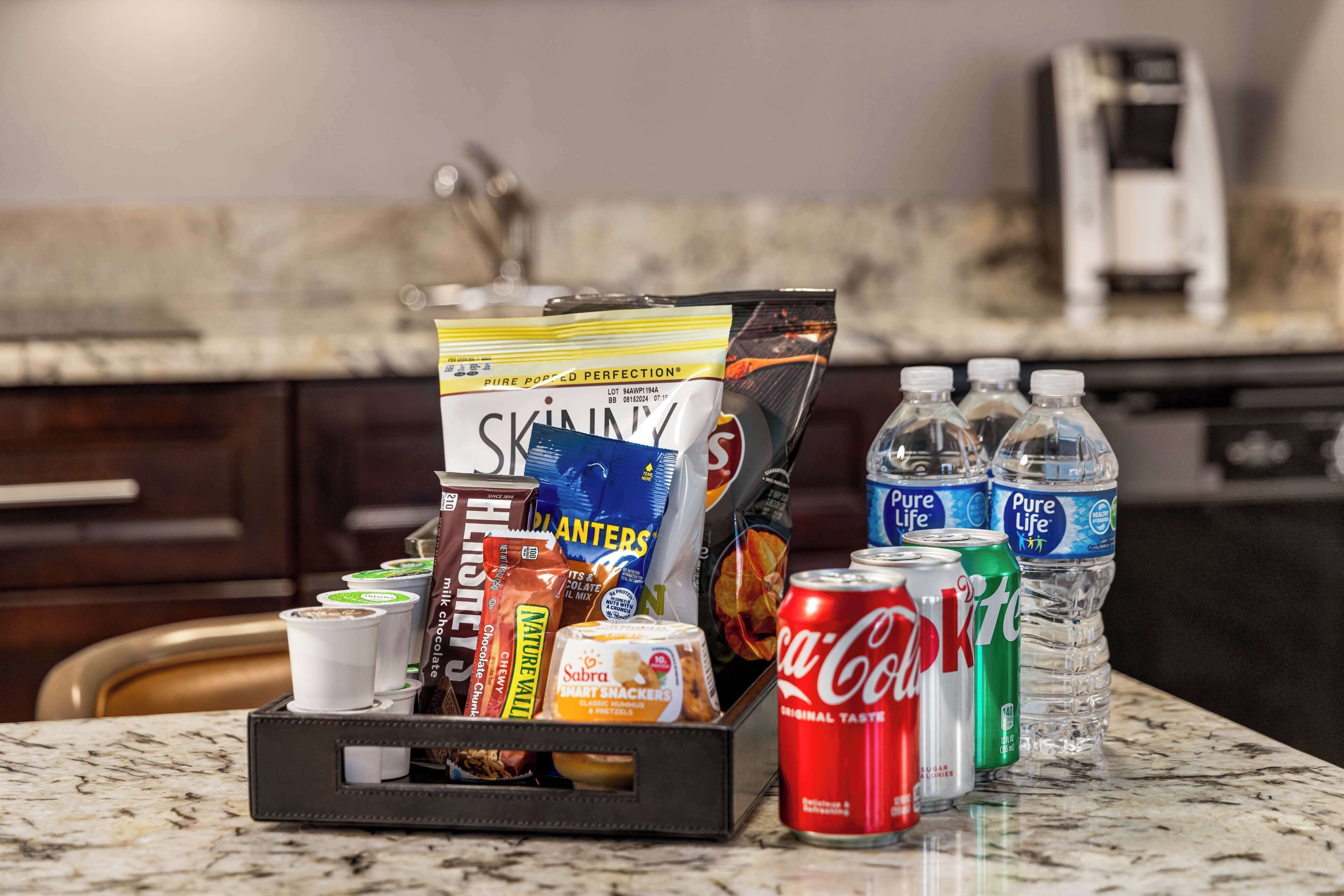 Een keukentrap met een koffiezetapparaat, een doosje snacks, flessen water en een blik Coca-Cola.