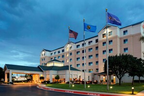 A hotel with a large building, multiple windows, and flags. - Hilton Garden Inn Oklahoma City Airport (Oklahoma City)
