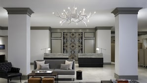Un salon moderne comprenant un canapé, des poufs, une table basse et un lustre original.