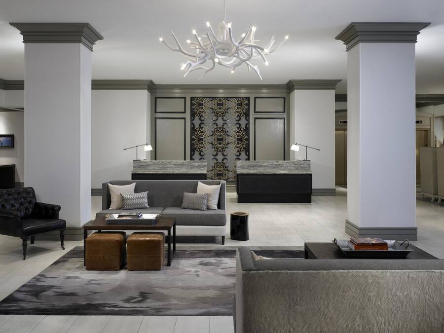 A modern living room with a sofa, ottomans, a coffee table, and a unique chandelier.