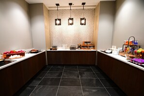 Una cocina moderna con una isla central, piso de baldosas negras e iluminación empotrada.
