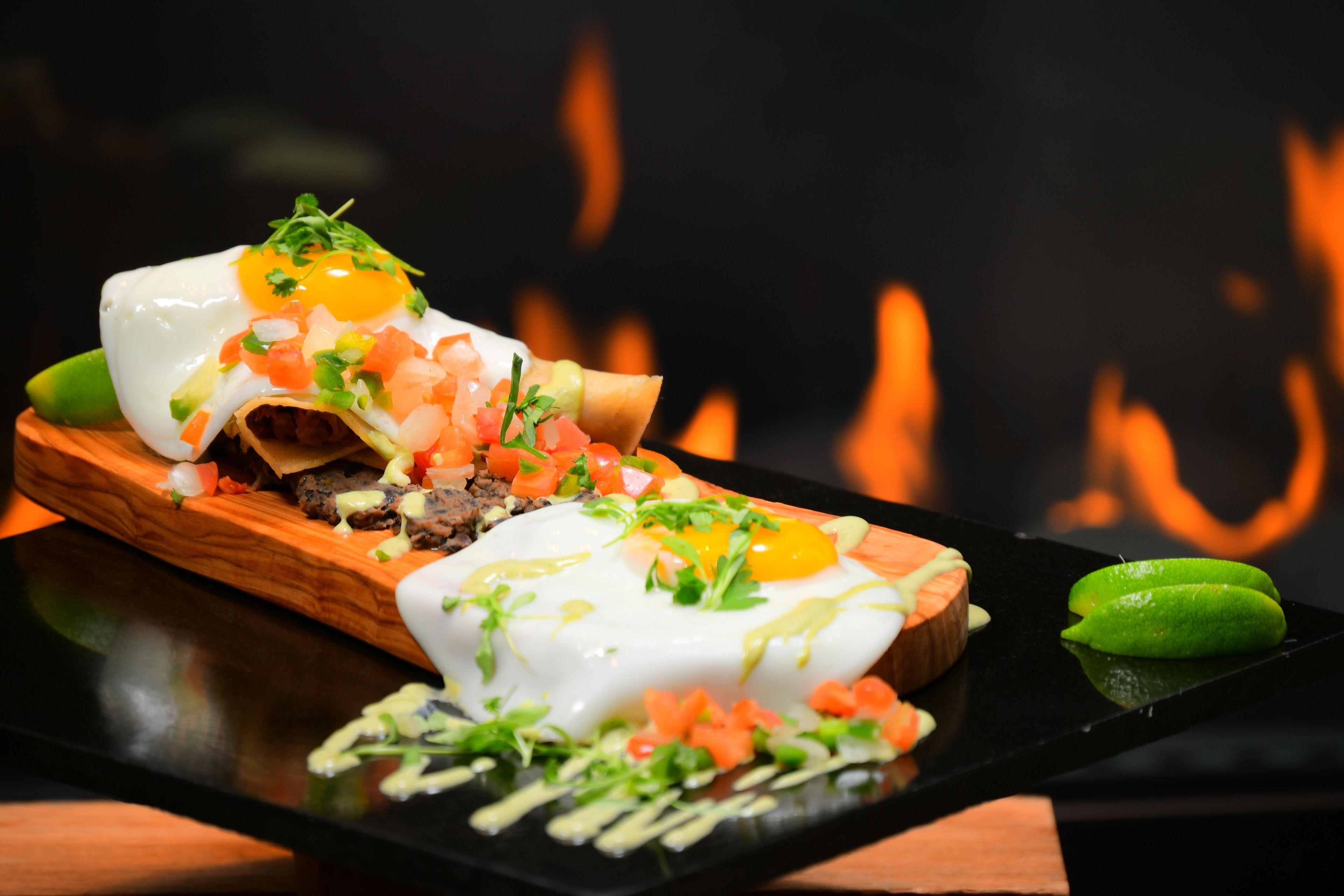 A dish with eggs, meat, and vegetables on a wooden board.