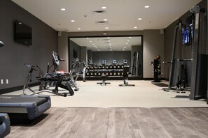 Un gimnasio con cintas de correr, elípticas y máquinas de pesas.