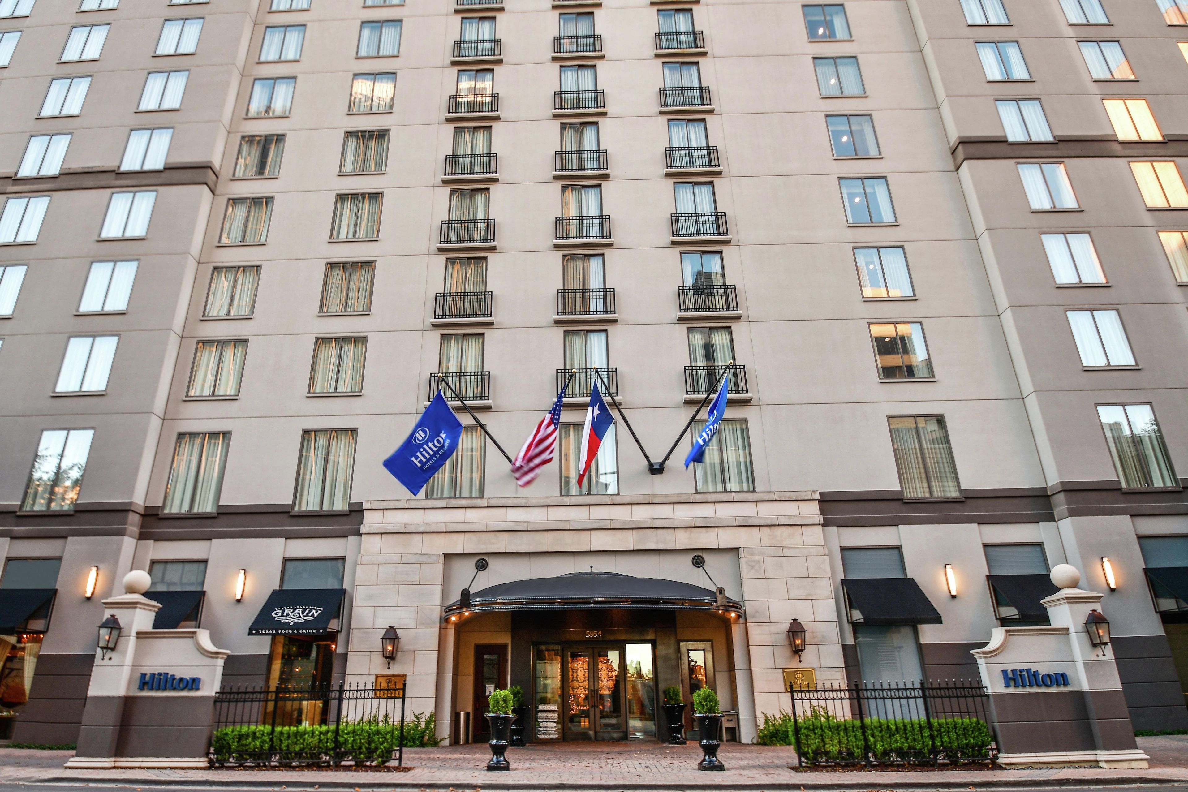 A multi-story hotel with a modern facade, multiple balconies, and flags.