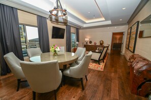 A modern hotel room with a dining area featuring a round table, six chairs, and a chandelier. - Hilton Dallas/Park Cities (Dallas)