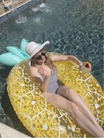 Una persona relajándose en un flotador inflable amarillo en una piscina transparente.