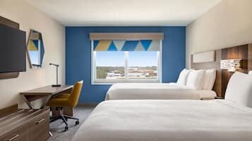 A hotel room with a desk, two beds, a TV, and a window with a view.