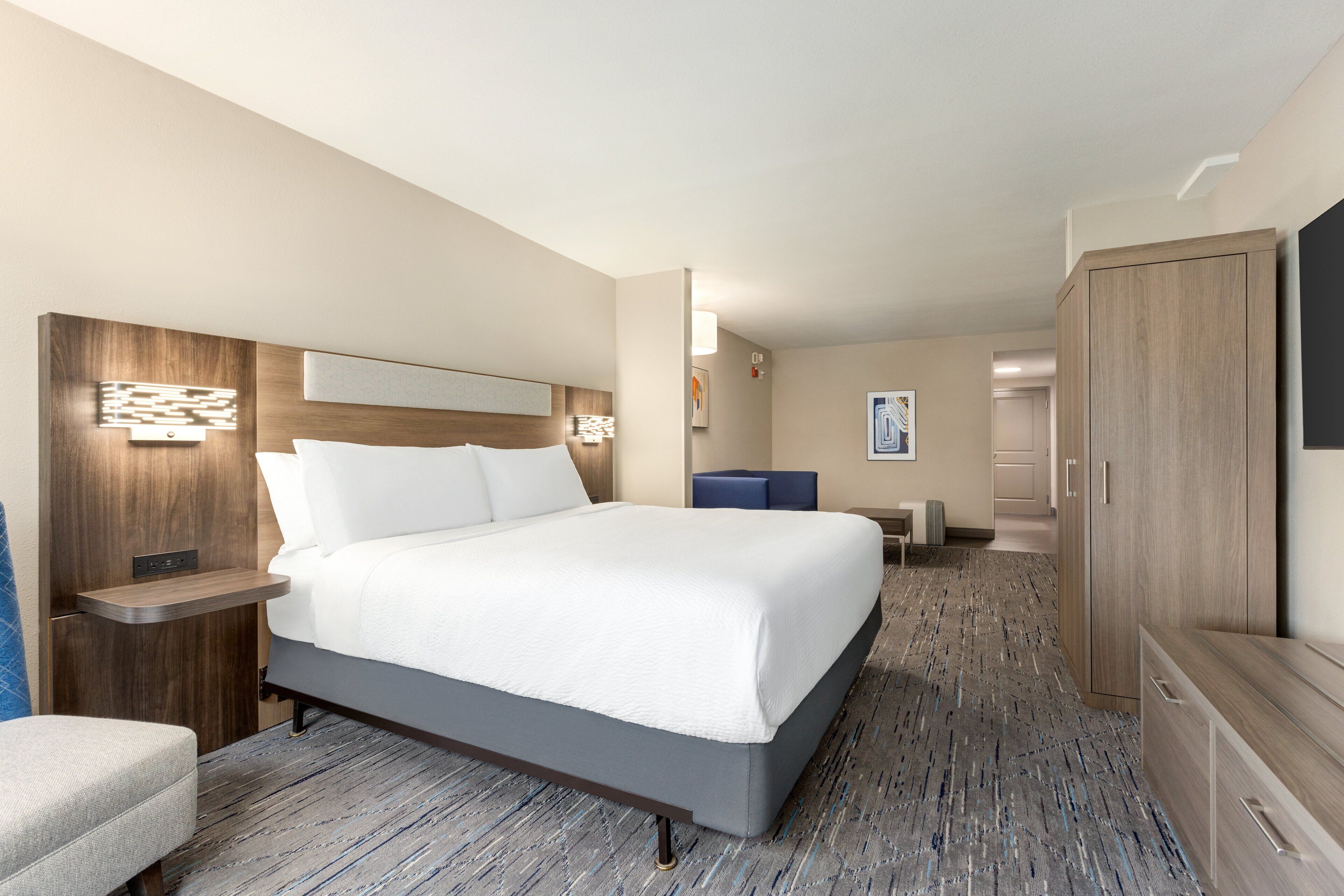 Ein Hotelzimmer mit einem großen Bett, einem Schreibtisch, einem Stuhl, einem Kleiderschrank und einem Fernseher.