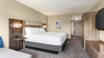 A hotel room with a large bed, bedside tables, a flat-screen TV, and a wardrobe.