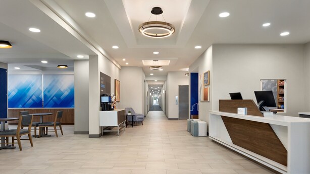 A modern reception area with a long corridor, a reception desk, and a seating area with tables and chairs. - Holiday Inn Express Hotel & Suites Fort Pierce West by IHG (Fort Pierce)