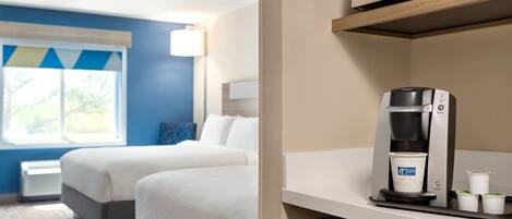 A hotel room with two beds, a microwave, a coffee maker, and a window with a view.