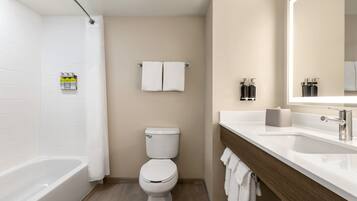 A modern bathroom with a bathtub, toilet, and vanity.