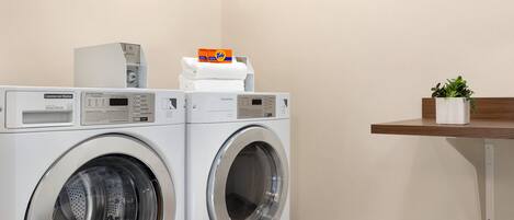 A commercial washer with a control panel and a detergent box on top.