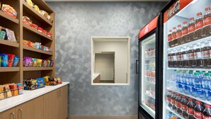 A snack bar with shelves stocked with various snacks and a Coca-Cola refrigerator. - Holiday Inn Express Hotel & Suites Fort Pierce West by IHG (Fort Pierce)