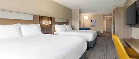 Habitación de hotel con dos camas, un escritorio, una silla y un televisor.