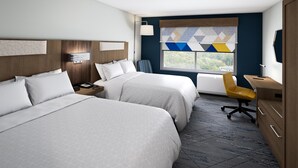 A hotel room with two beds, a desk, a chair, a nightstand, and a window with a view.