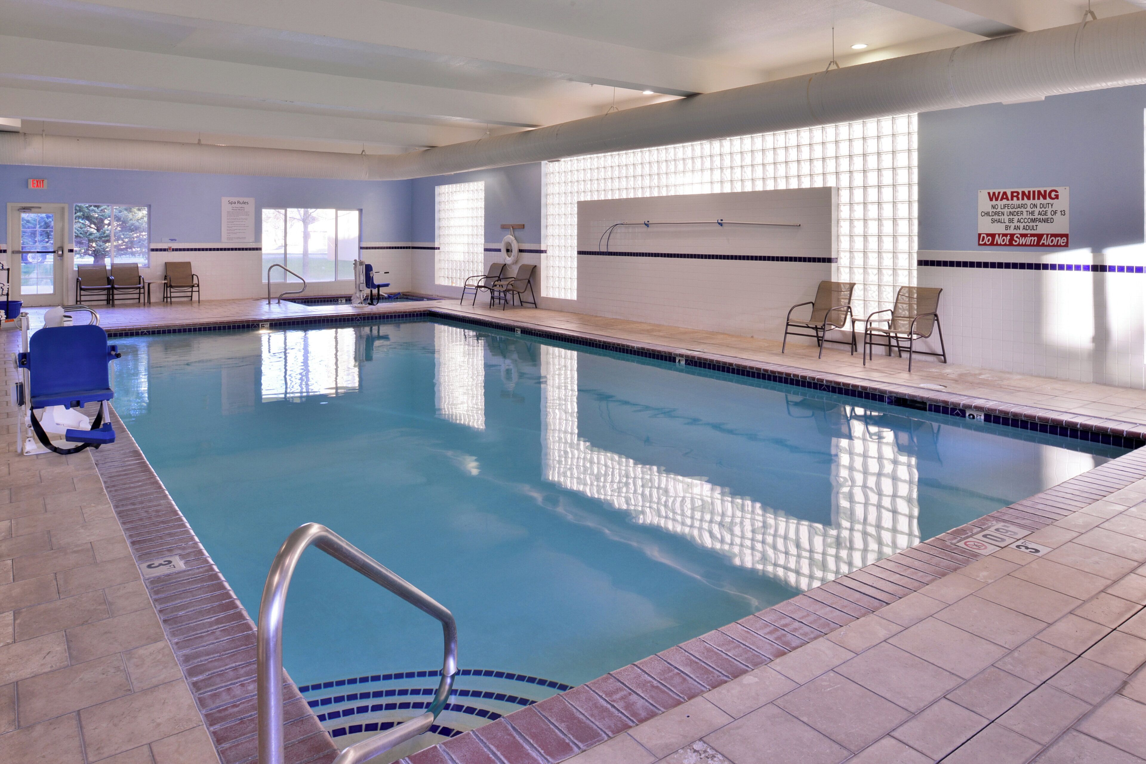 Une piscine intérieure à l’eau claire, dotée d’un poste de surveillance pour les sauveteurs et de chaises longues.