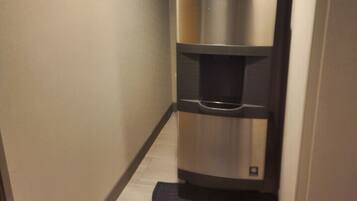 A narrow hallway with a stainless steel refrigerator and water dispenser.